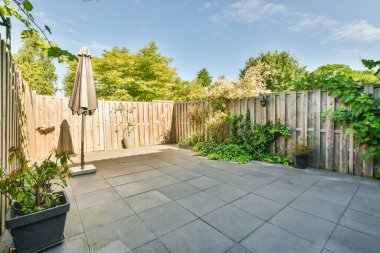 Ahşap çitlerin yanında küçük bahçesi olan basit küçük bir teras.