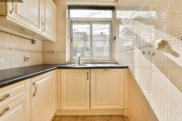 Çağdaş dairenin geniş odasındaki dinlenme odası ve mutfağın yakınındaki sandalyeli ve çiçekli masa.