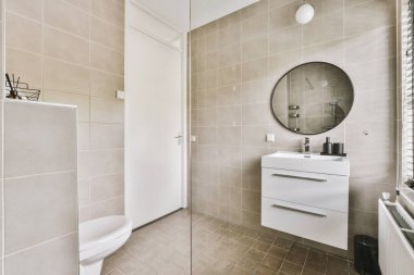 Modern sifon tuvaleti ve seramik lavabo aynanın yanındaki beyaz fayanslı duvarlara ve evdeki küçük tuvaletteki havluya monte edildi.