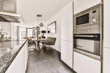 Minimalist tarzı açık mutfağı ve masa ve sandalyeleri olan geniş yemek alanı olan modern çatı katı dairesinin ev tasarımı.