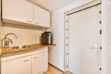 Minimalist tarzı beyaz mobilyalı, lavabolu ve sobalı bir ev mutfağı.