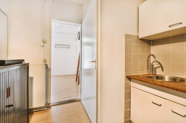 Minimalist tarzı beyaz mobilyalı, lavabolu ve sobalı bir ev mutfağı.