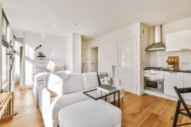 Günümüz minimalist tasarımı. Hafif stüdyo dairesinin ahşap masası ve oturma odası ile beyaz duvarları ve parke zemini arasında yemek masası ve sandalyeleri var.