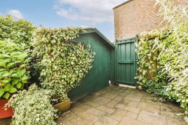 Oturma alanı ve ahşap çitlerin yanındaki küçük bahçesi olan düzgün asfaltlı bir avlu.