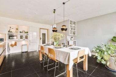 Günümüz minimalist tasarımı. Hafif stüdyo dairesinin ahşap masası ve oturma odası ile beyaz duvarları ve parke zemini arasında yemek masası ve sandalyeleri var.