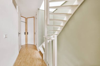 Minimalist iç tasarımı olan modern lüks dairenin ikinci katına çıkan ahşap merdivenli beyaz koridor.