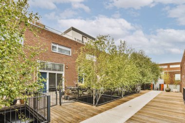 Ağaçlar ve fenerlerle dolu boş bir kaldırım sokağından tuğla evler manzarası