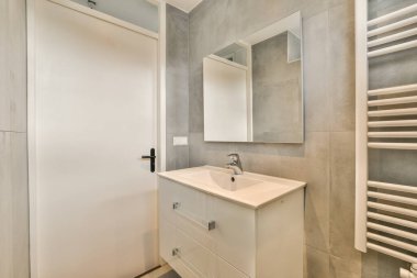 Havlulu raflar ve lavaboların yanında duran kurutma rafları aynalar ve modern dairenin banyolarında küvet.