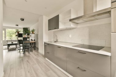 Modern minimalist tarzda iç tasarım stüdyo dairesinin açık beyaz mutfağı ve masa ve sandalyeli yemek alanı