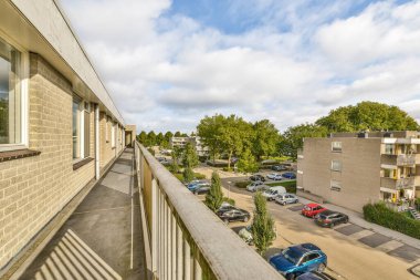 Eski tuğla binaların panoramik manzarası. Küçük balkondan park yerleri ve ağaçlar.