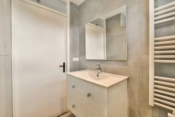 在现代化公寓的轻便浴室里 靠近水槽 镜子和浴缸的有毛巾和烘干架的架子 — 图库照片