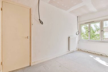 Evdeki boş ışık odasında, beyaz duvardaki plastik pencere ve radyatör.