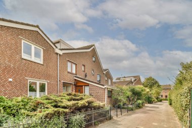 Arabaları, ağaçları ve fenerleri olan boş bir kaldırımdan panorama manzaralı evler.