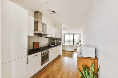 Günümüz minimalist tasarımı. Hafif stüdyo dairesinin ahşap masası ve oturma odası ile beyaz duvarları ve parke zemini arasında yemek masası ve sandalyeleri var.