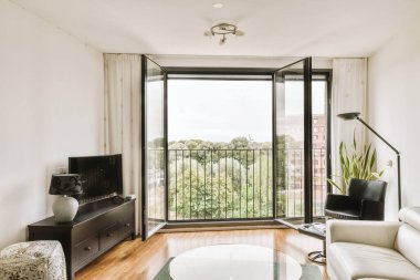 Günümüz minimalist tasarımı. Hafif stüdyo dairesinin ahşap masası ve oturma odası ile beyaz duvarları ve parke zemini arasında yemek masası ve sandalyeleri var.