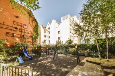 Arabaları, ağaçları ve fenerleri olan boş bir kaldırımdan panorama manzaralı evler.