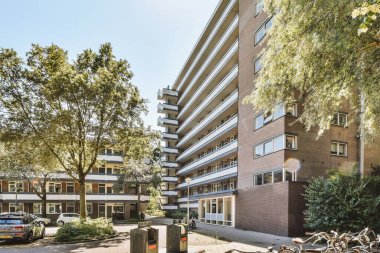 Arabaları, ağaçları ve fenerleri olan boş bir kaldırımdan panorama manzaralı evler.