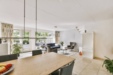 Günümüz minimalist tasarımı. Hafif stüdyo dairesinin ahşap masası ve oturma odası ile beyaz duvarları ve parke zemini arasında yemek masası ve sandalyeleri var.