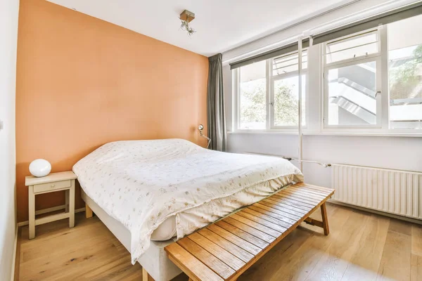 stock image Home interior design of bedroom with bed and wooden wardrobe placed in corner near window in modern apartment