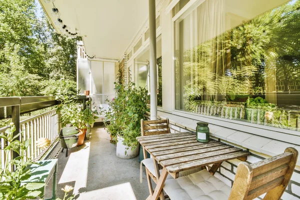 Stock image Narrow brick balcony with metal railings, wooden chair and door with glass leads to the kitchen