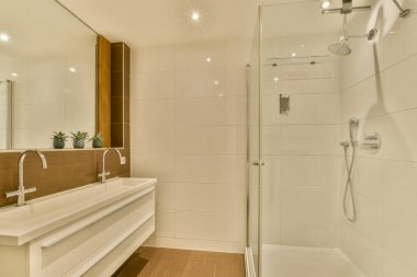 Evdeki modern tuvalette asılı duran banyo musluğu ile duvar arasındaki cam bölme.