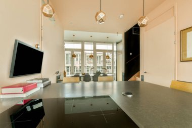 TV 'nin yanındaki koltuklar ve masa, çağdaş apartmandaki geniş odalı yemek alanına karşıdır.