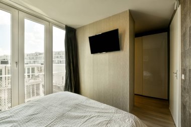 Geniş yataklı ve geniş pencereli, hafif yatak odasının içi.