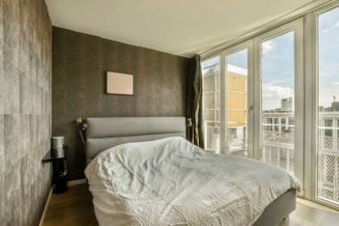 Geniş yataklı ve geniş pencereli, hafif yatak odasının içi.