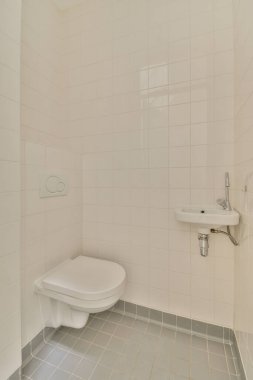 Lavabolu ve duvarlı, beyaz duvarlı ve kareli tuvaletli dar bir tuvalet.