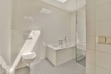 Aynalı lavabo ve temiz küvet modern banyoda cam kapılı ve beyaz fayanslı duvarları olan duş kutusunun yanında.