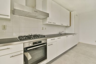 Modern ev mutfağı iç tasarımı beyaz dolaplar, dolaplar ve çelik kapüşon ile çağdaş apartmanda.