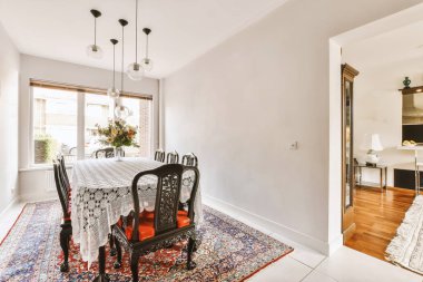 Günümüz minimalist tasarımı. Hafif stüdyo dairesinin ahşap masası ve oturma odası ile beyaz duvarları ve parke zemini arasında yemek masası ve sandalyeleri var.