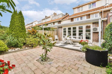 Oturma alanı ve ahşap çitlerin yanındaki küçük bahçesi olan düzgün asfaltlı bir avlu.