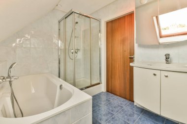 Aynalı lavabo ve temiz küvet modern banyoda cam kapılı ve beyaz fayanslı duvarları olan duş kutusunun yanında.