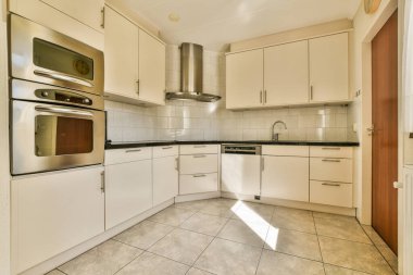 Stüdyo dairesinin modern minimalist tarzı iç tasarımı açık beyaz mutfak ve yemek masası ve sandalyeleri tavan arası lambasıyla aydınlatılmış.