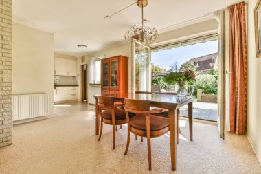 Stüdyo dairesinin modern minimalist tarzı iç tasarımı açık beyaz mutfak ve yemek masası ve sandalyeleri tavan arası lambasıyla aydınlatılmış.