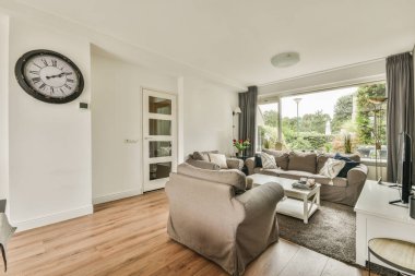 Çağdaş dairenin geniş odasındaki dinlenme odası ve mutfağın yakınındaki sandalyeli ve çiçekli masa.