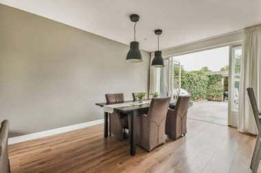 Çağdaş dairenin geniş odasındaki dinlenme odası ve mutfağın yakınındaki sandalyeli ve çiçekli masa.