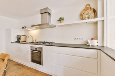 Günümüz minimalist tasarımı. Hafif stüdyo dairesinin ahşap masası ve oturma odası ile beyaz duvarları ve parke zemini arasında yemek masası ve sandalyeleri var.