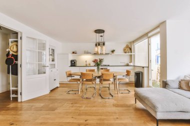 Günümüz minimalist tasarımı. Hafif stüdyo dairesinin ahşap masası ve oturma odası ile beyaz duvarları ve parke zemini arasında yemek masası ve sandalyeleri var.