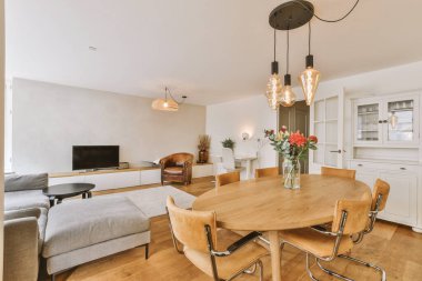 Günümüz minimalist tasarımı. Hafif stüdyo dairesinin ahşap masası ve oturma odası ile beyaz duvarları ve parke zemini arasında yemek masası ve sandalyeleri var.