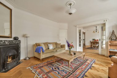 Işıl ışıl mobilyaları ve yumuşak rahat kanepesi ve halısı olan oturma odasının şık iç tasarımı ve modern bir dairede, açık mutfak, beyaz duvarlar ve sütunları olan televizyon..