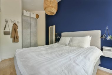 Comfortable bed covered with blanket and located in light bedroom of modern apartment