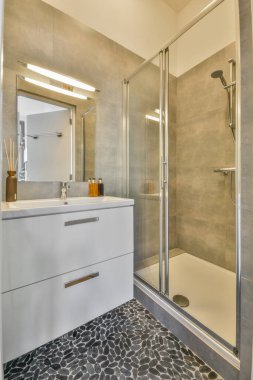 Evdeki modern tuvalette asılı duran banyo musluğu ile duvar arasındaki cam bölme.