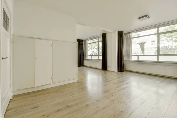 带有窗帘和木制地板的全景窗户的空白色房间的内部 — 图库照片
