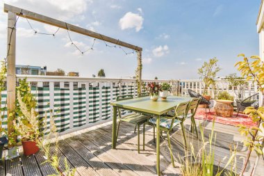 Bright brick balcony with metal railings, wooden chair and door with glass leads to the kitchen