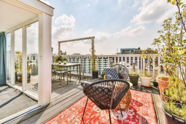 Bright brick balcony with metal railings, wooden chair and door with glass leads to the kitchen