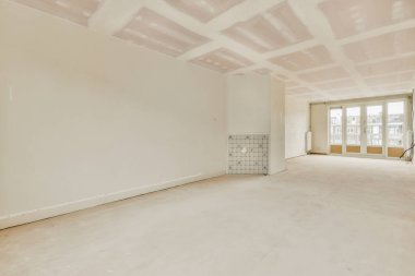 Gündüz vakti pencereleri ve radyatörü olan boş bir oda.