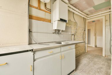 Küçük boş mutfak ve evdeki balkon kapısının yanında lavabosu olan mobilyalar.