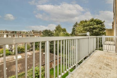 Panoramic view of brick buildings with parking and trees from small balcony